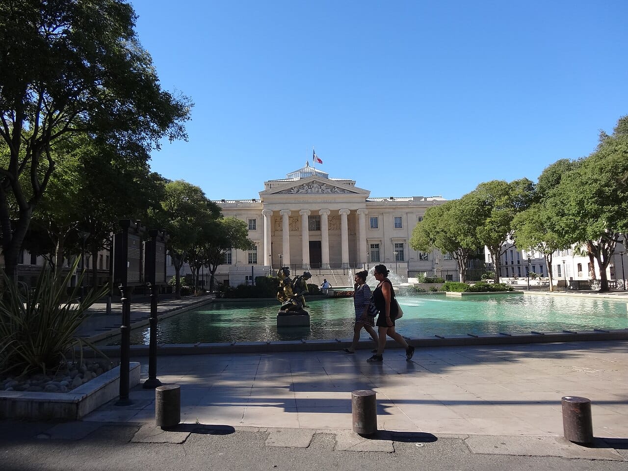 Palais de justice de Marseille derrière un bassin et des arbres.