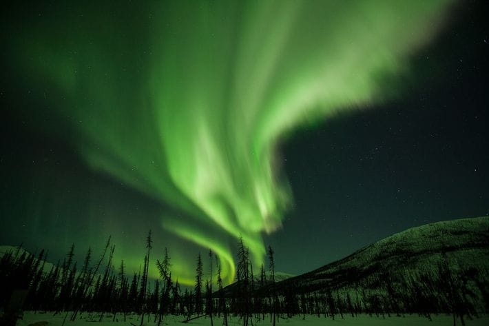 Des rideaux de lumière bordent le ciel de l'Alaska. Connus sous le nom de lueurs boréales ...