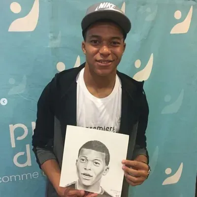 Kylian Mbappé qui pose avec son portrait.
