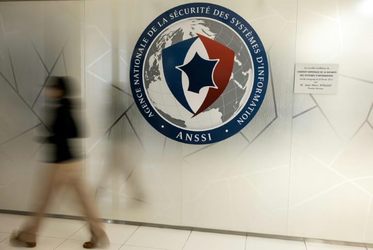Une silhouette floue en mouvement passe devant le grand sceau mural de l’Agence nationale de la sécurité des systèmes d’information
