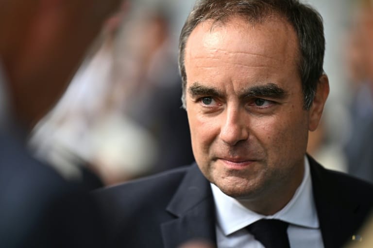 Portrait rapproché du Premier ministre Sébastien Lecornu, de profil trois quarts, entouré de silhouettes floues