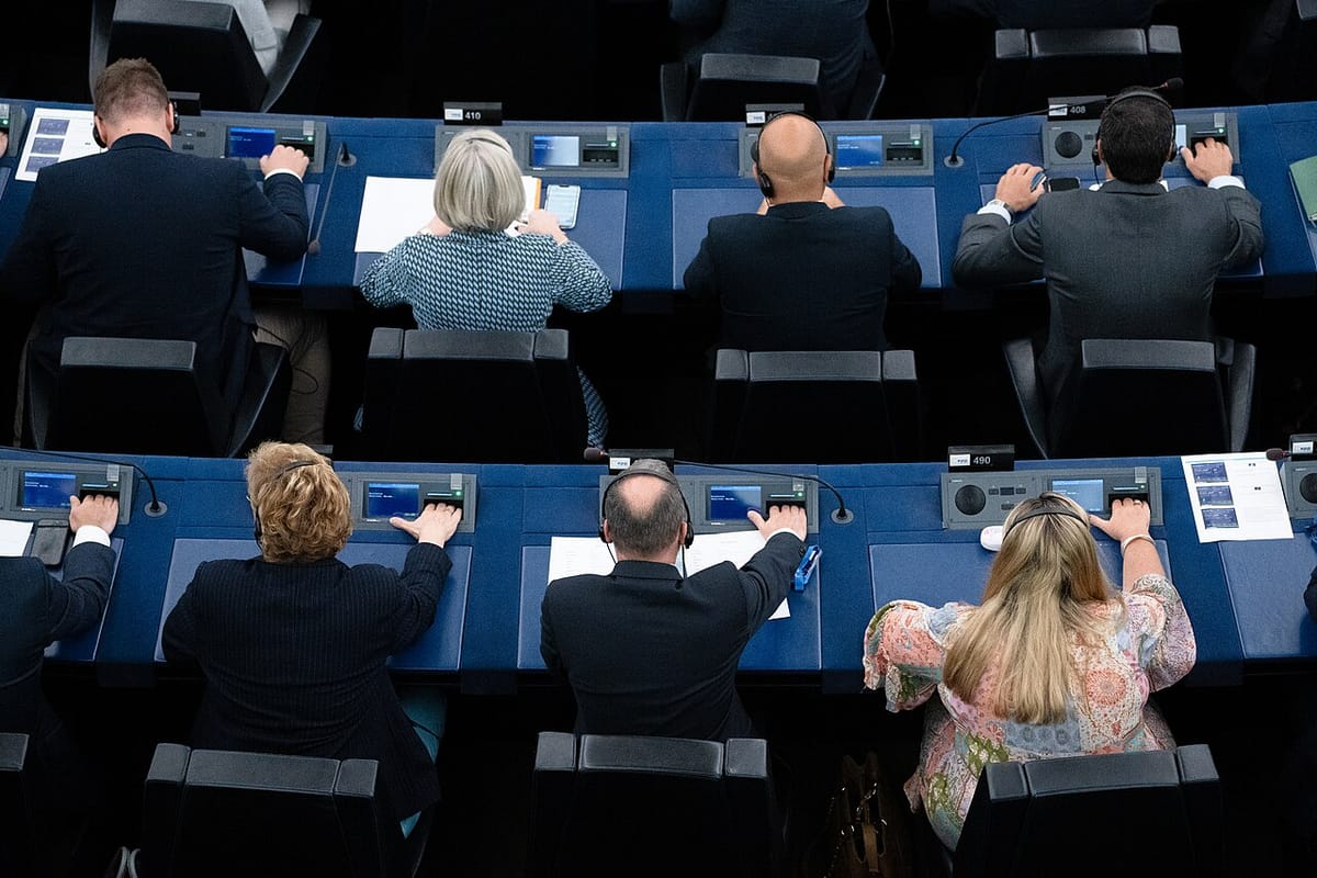 Vue de dessus de députés européens assis à leurs pupitres, la main posée sur le boîtier de vote pendant une séance