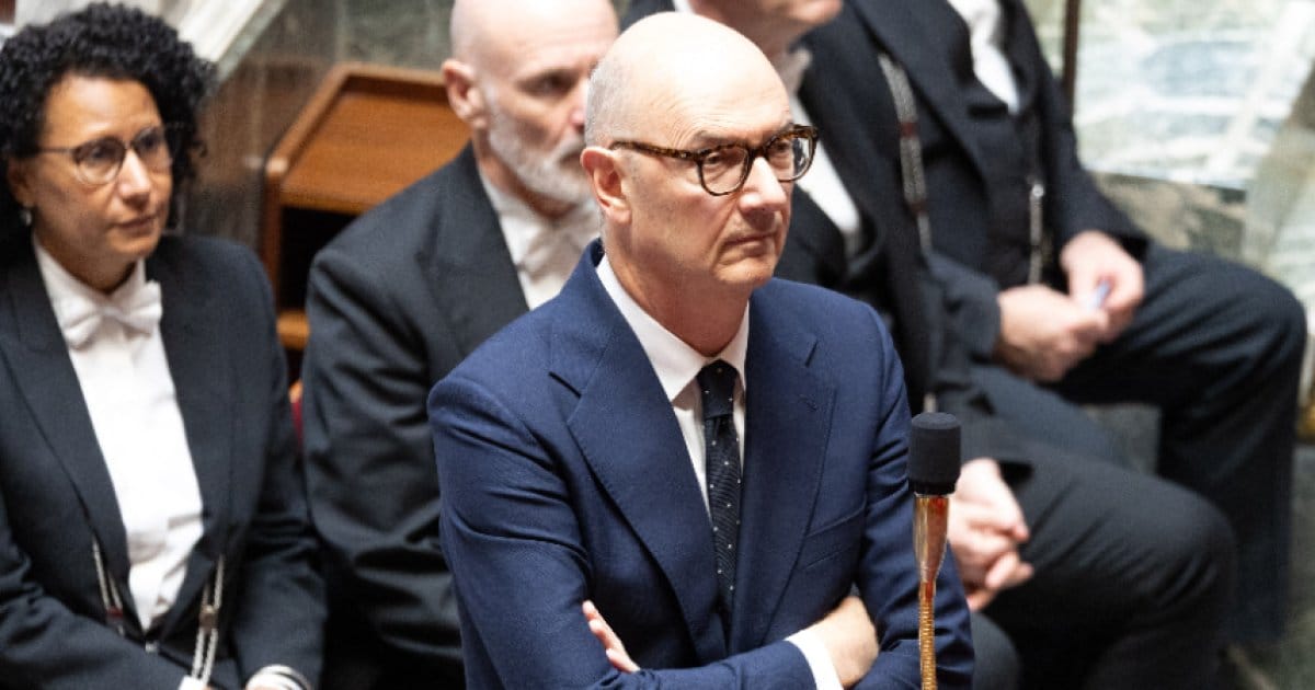 Roland Lescure, ministre de l’Économie, bras croisés sur les bancs du gouvernement dans l’hémicycle de l’Assemblée nationale.