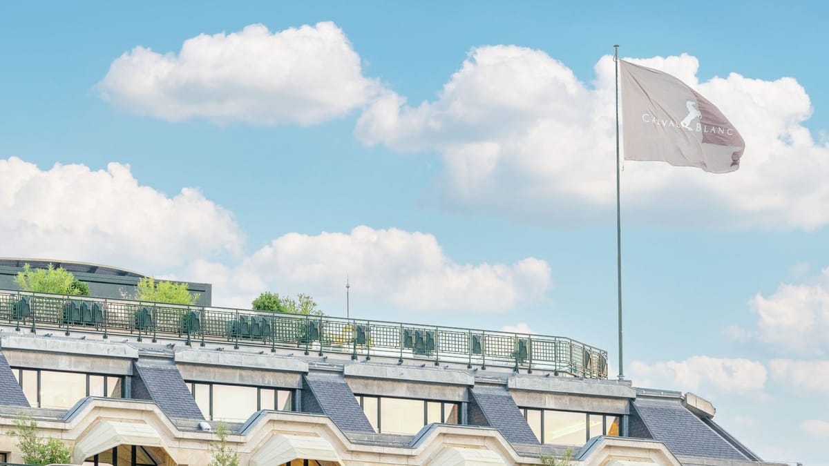 Un pavillon blanc portant le monogramme Cheval Blanc flotte au vent au sommet du toit de l’ancien bâtiment de la Samaritaine, à Paris, sous un ciel de nuages.