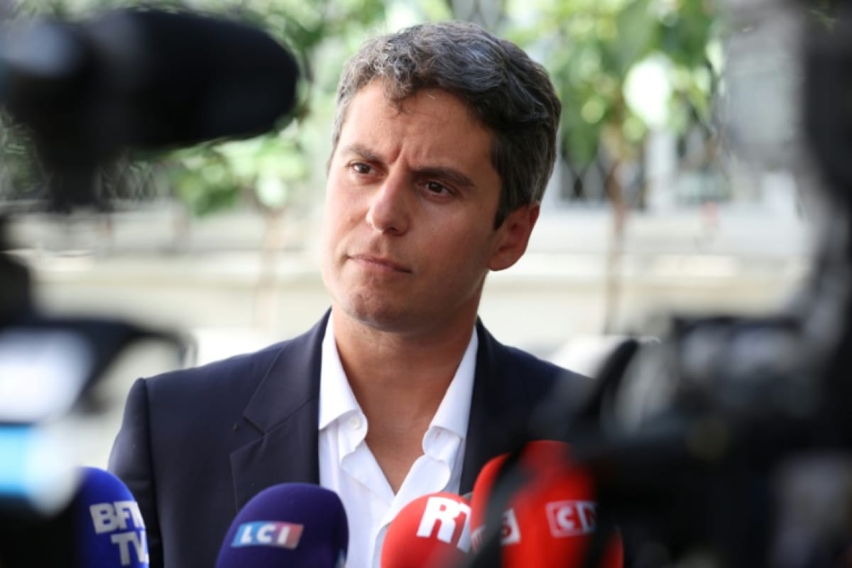 Gabriel Attal entouré de micros de télévision et de caméras