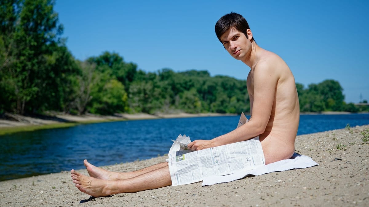 Julien Ferrat assis sur une plage, le bulletin municipal posé sur les jambes