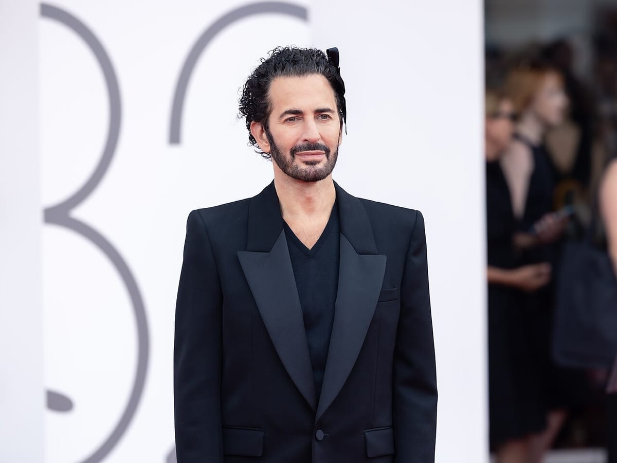 Le créateur Marc Jacobs, en costume noir et ruban noir dans les cheveux, sur le tapis rouge de la Mostra de Venise.