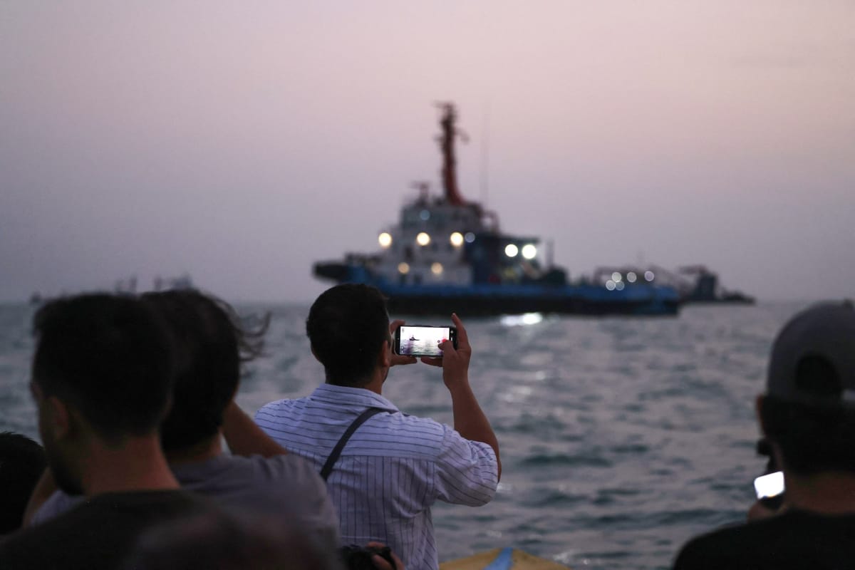 Des passagers d’un bateau photographient un navire de commerce qui traverse le détroit d’Ormuz, au large de Bandar Abbas, dans le sud de l’Iran.
