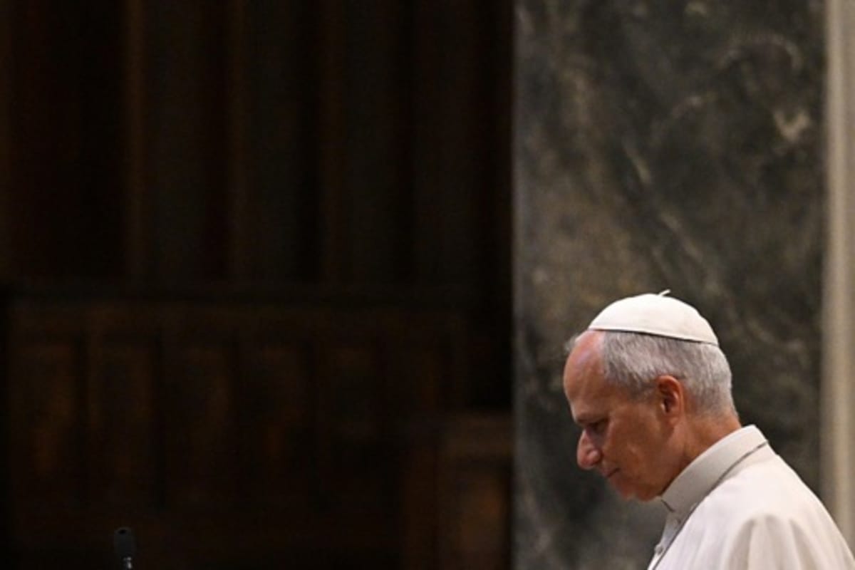 Le pape Léon XIV de profil, calotte blanche, tête baissée, devant une paroi de marbre sombre.