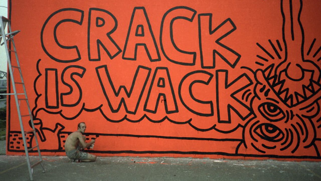 American pop artist and activist Keith Haring (1958 - 1990) paints the original version of his 'Crack is Wack' mural on the wall of a hand ball court in a public park (at East 128th Street and 2nd Avenue, alongside Harlem River Drive), New York, New York , summer 1986. This first version of the mural, painted in response to the then-ongoing epidemic of crack cocaine usage in New York, was executed illegally and was subsequently completely repainted with different imagery (and legally, with the blessing of the city's government who renamed the park the 'Crack is Wack Playground') at least once by Haring in the following months. (Photo by Juan Rivera/Roulette Fine Art/Getty Images)